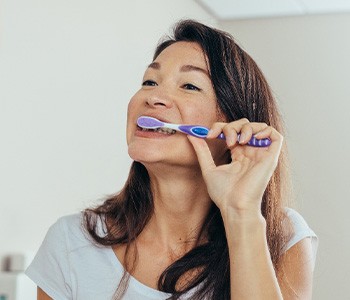 Woman brushing her teeth in bathroom