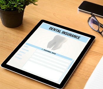 Dental insurance form on tablet next to notepad