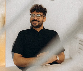 Patient with black glasses smiling in treatment chair