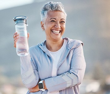 Woman smiling with water bottle on hike outside
