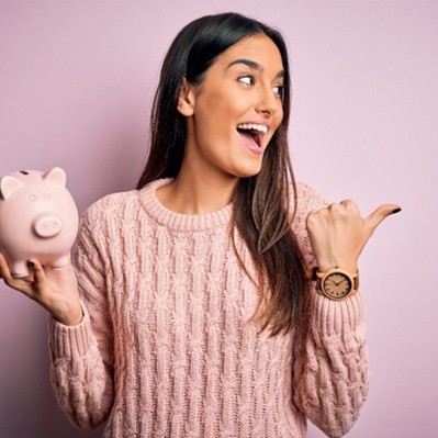 a patient smiling and holding a piggy bank