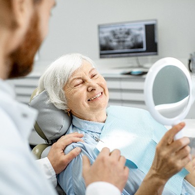 Senior woman smiling at reflection in handheld mirror