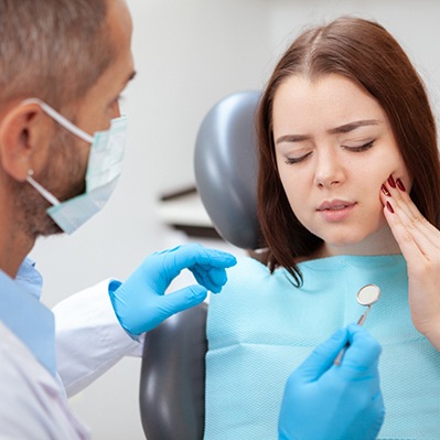 A pained woman seeing her dentist for a dental emergency