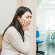 Woman with chipped or broken tooth holding cheek