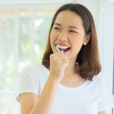 Woman brushing teeth to prevent dental emergencies