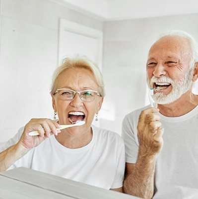Happy senior couple brushing their teeth in front of the mirror