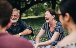 Group of adults smiling while sitting in a circle outside