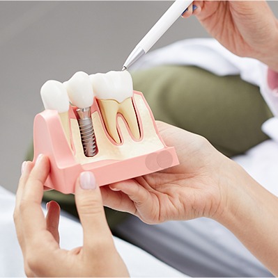 Dentist and patient looking at dental implant model