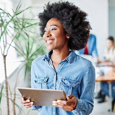 Woman smiling while holding tablet in office