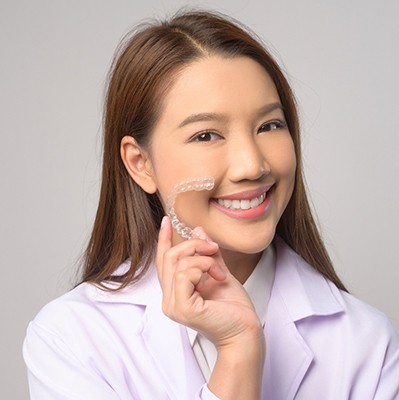 Smiling patient holding clear aligner
