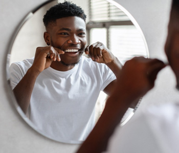 Man smiling while flossing his teeth