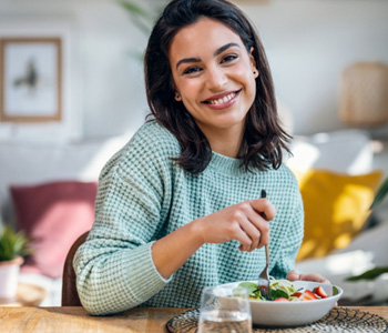 Woman smiling while eating lunch at home
