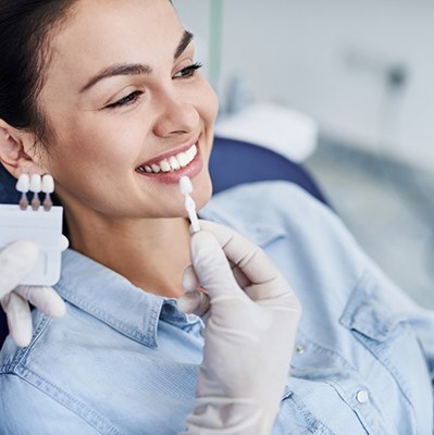 Dental patient looking in mirror, admiring the results of her smile makeover