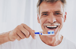 a dental implant patient brushing his teeth