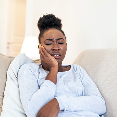 Woman on couch experiencing toothache