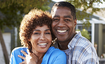 Man and woman smiling after replacing missing teeth