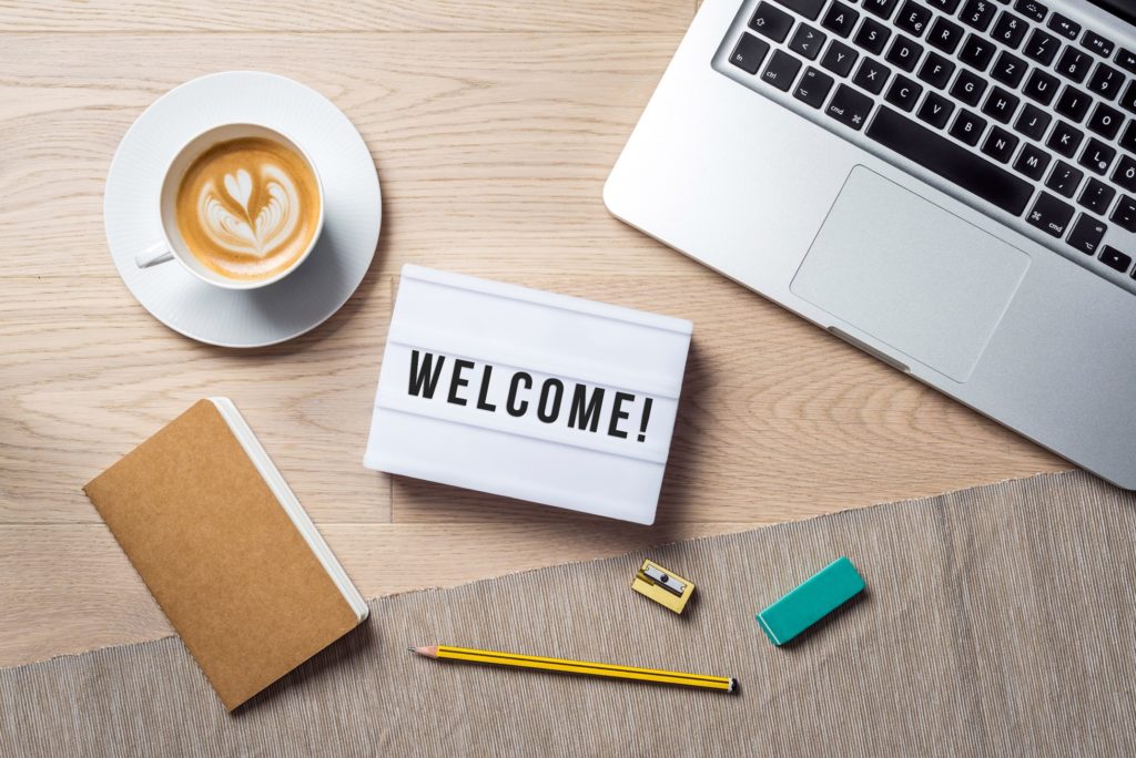 Welcome sign lying on desk next to laptop and supplies