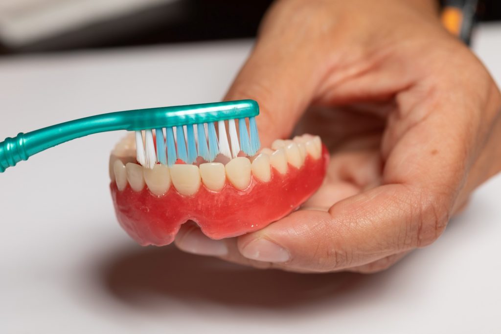 Closeup of patient cleaning denture