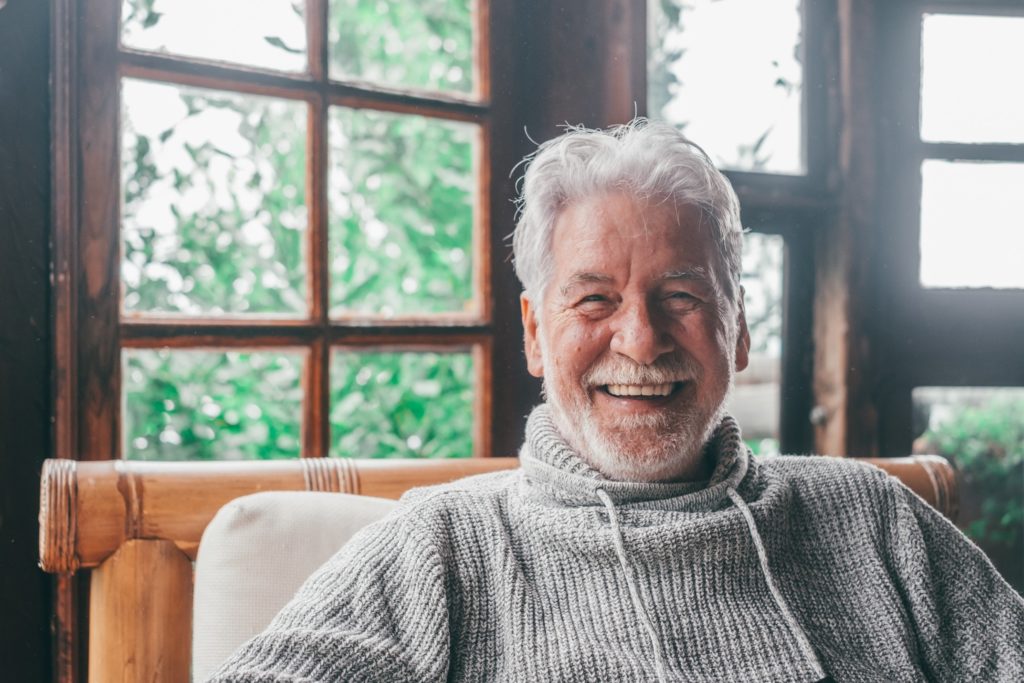 Man with dentures smiling on indoor porch