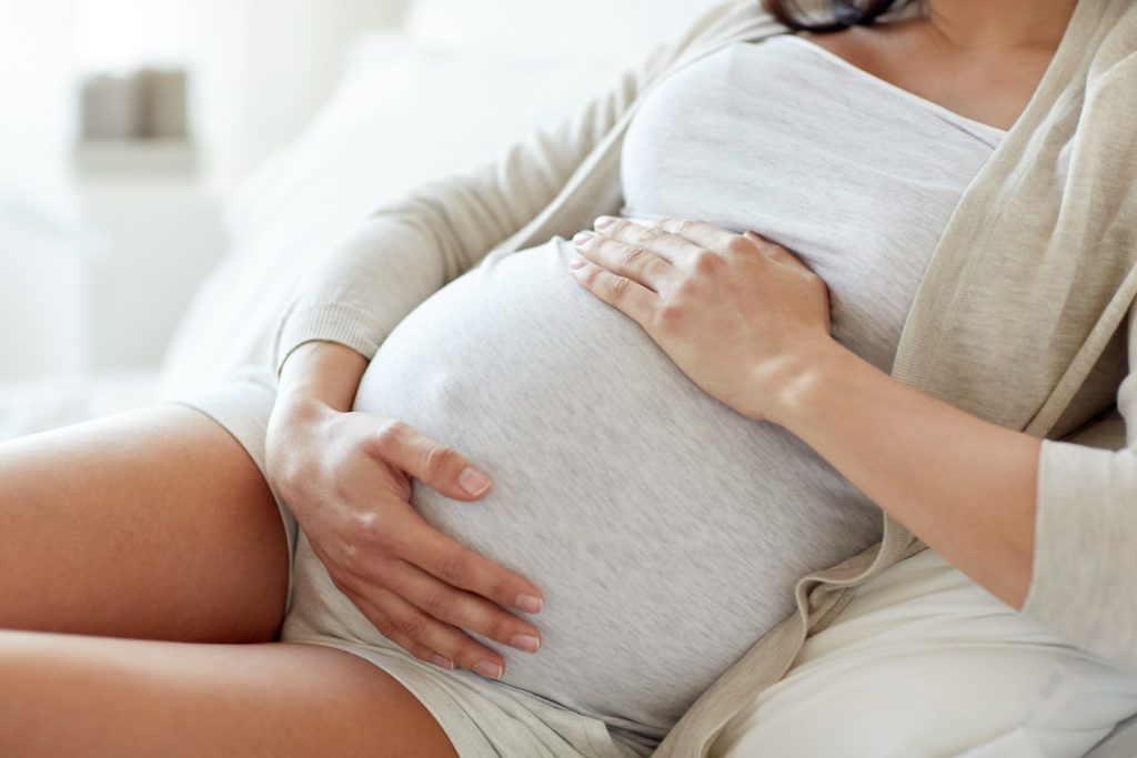 Closeup of woman relaxing and holding her baby belly