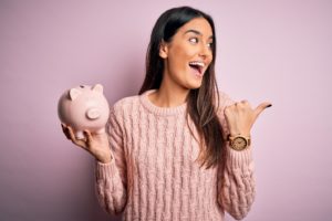 a woman smiling and holding a piggy bank