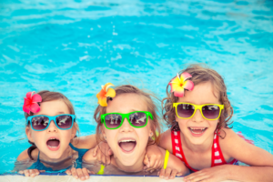 a group of children swimming in a pool during summer 