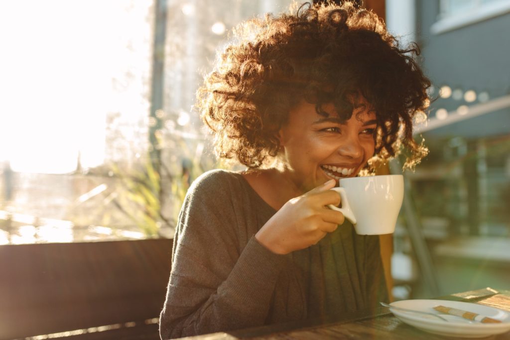 Smiling woman enjoying cup of coffee outside