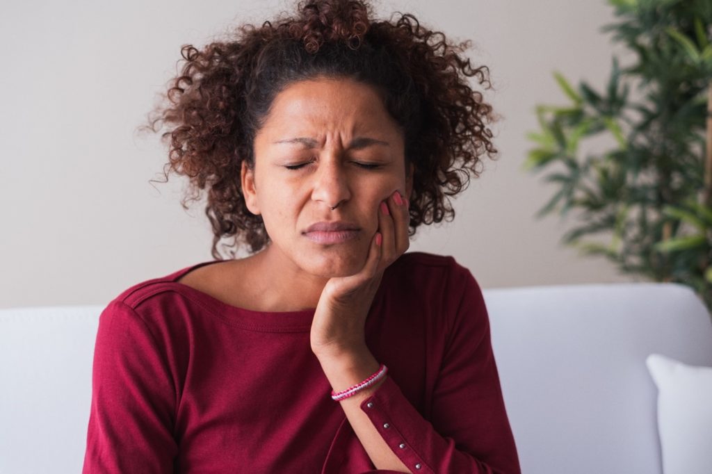 Woman with toothache sitting on couch at home