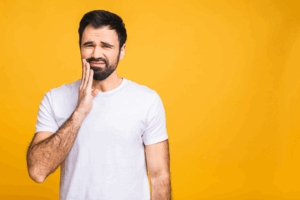 a man holding his jaw in pain due to an impacted wisdom tooth