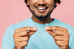 a patient smiling and holding their Invisalign aligner